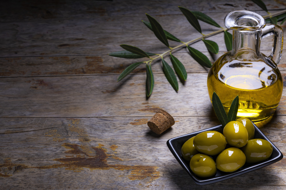 Olive oil and olive leaf on dark wooden background