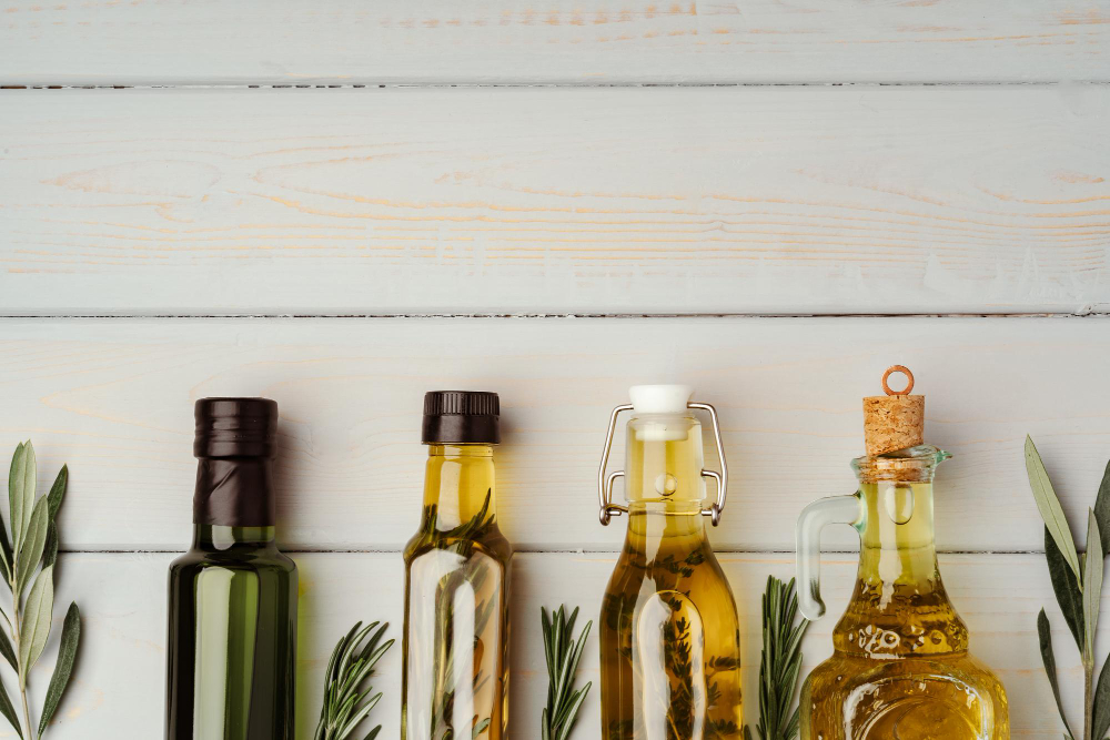 Glass bottle with olive and vegetable oils on gray background